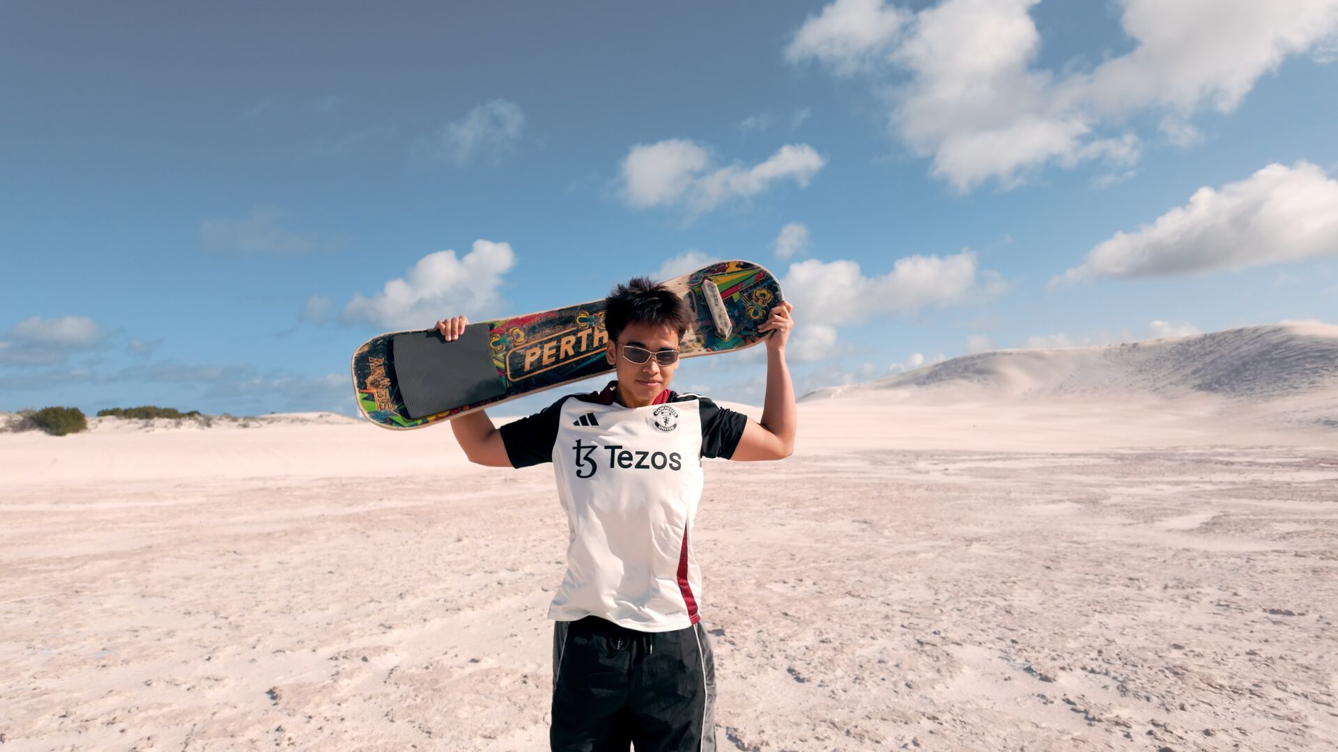 Image of Musa holding a sand board at the sand dunes in Lancelin
