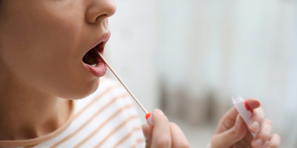 Woman taking sample for DNA test indoors, closeup