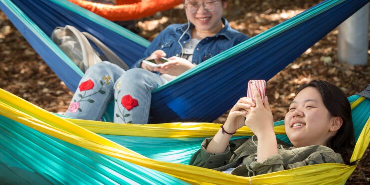Two students sitting on hammocks.