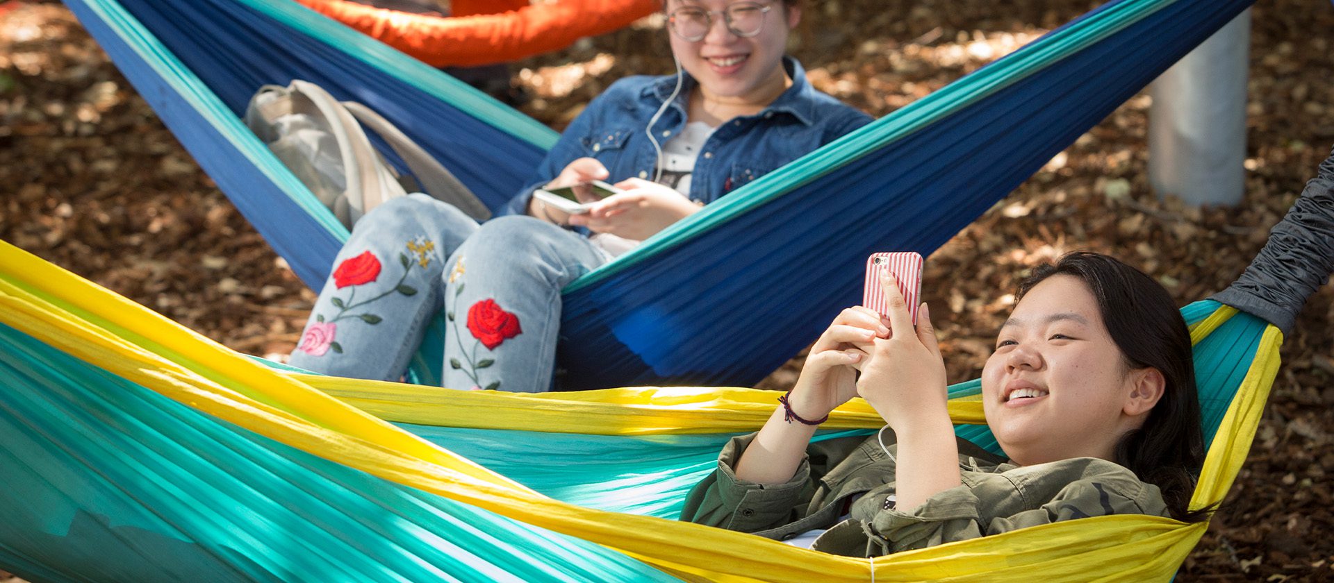 Two students sitting on hammocks.
