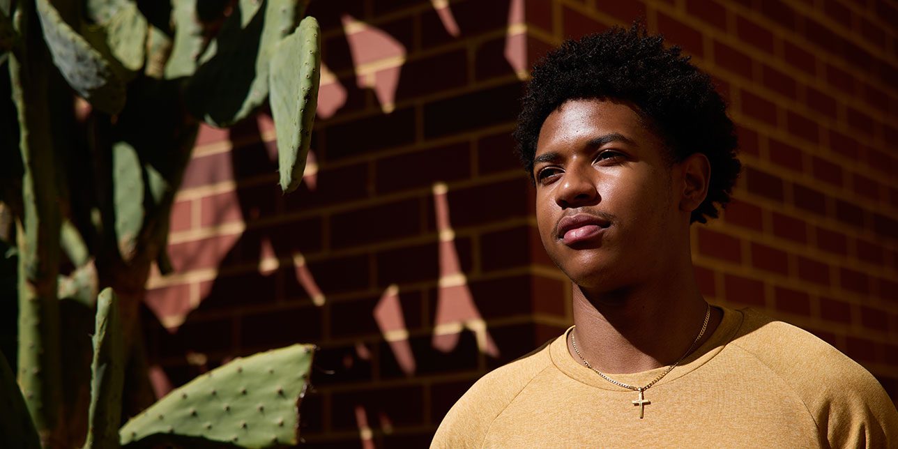 Curtin student in yellow tshirt looking wistfully off into the distance.