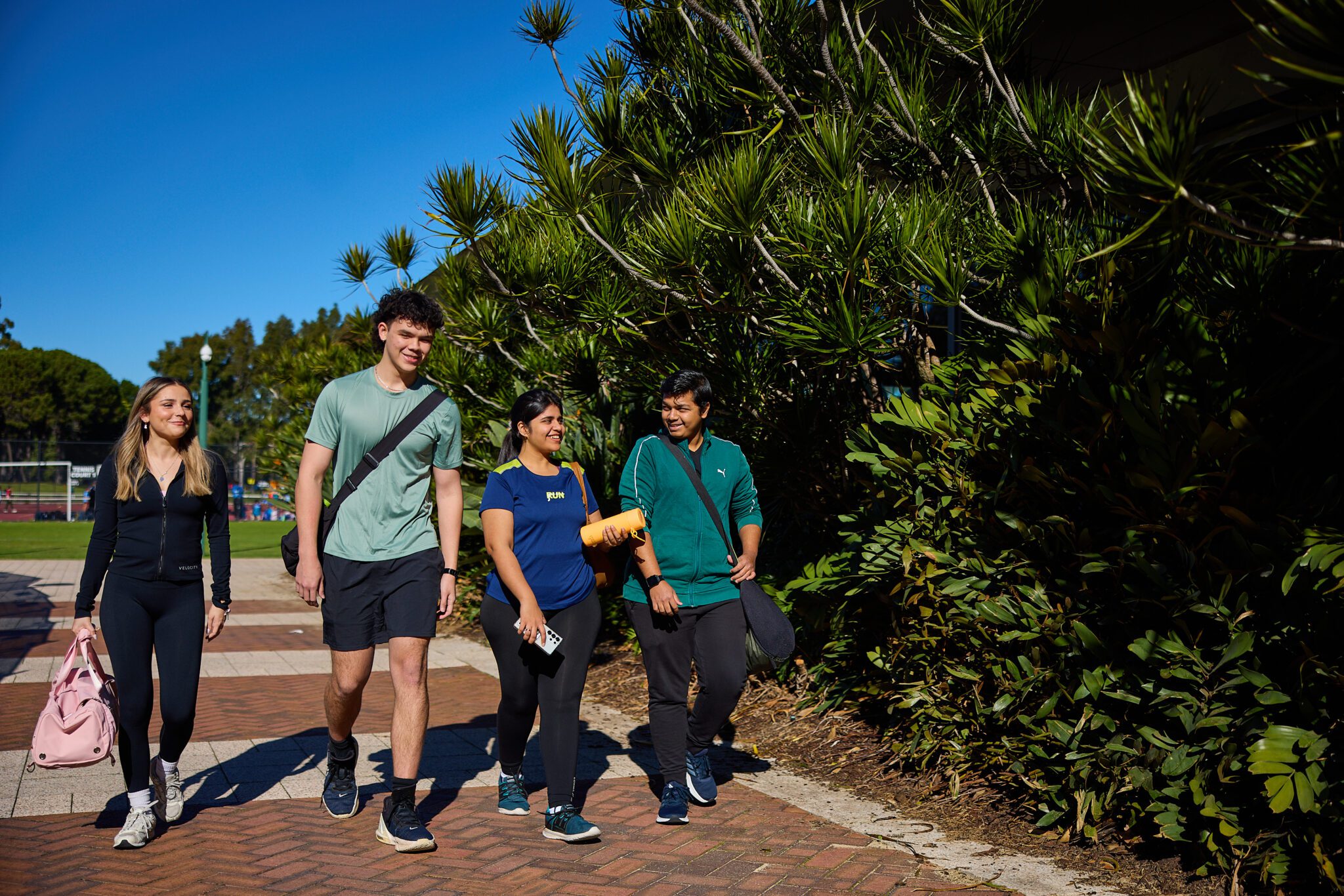Four students walking outside Curtin Stadium.