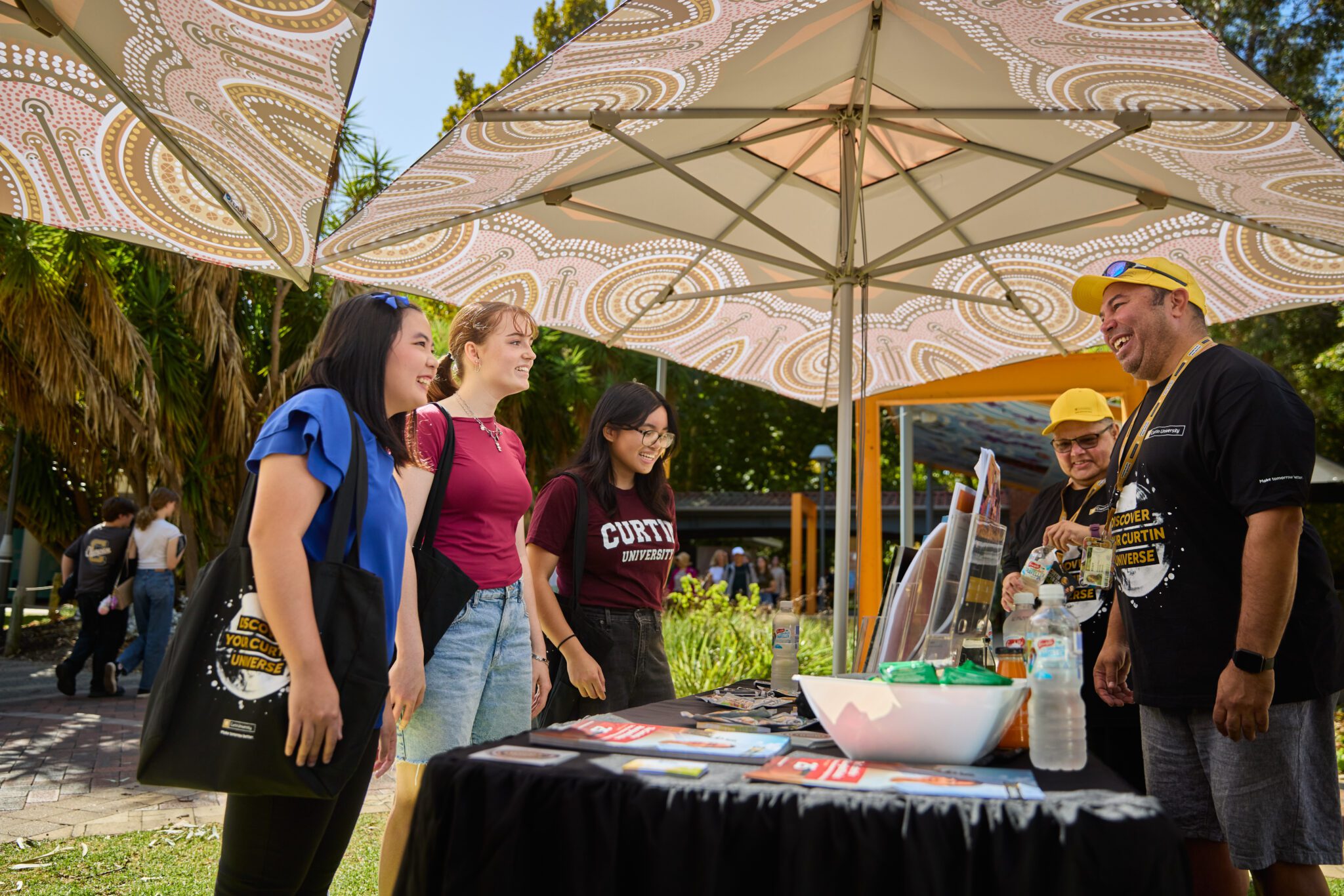 Future students exploring study options and asking questions at a Curtin Open Day information booth.