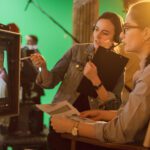 Female Director in Chair Looks at Display talks with Assistant, Shooting Blockbuster. Green Screen Scene