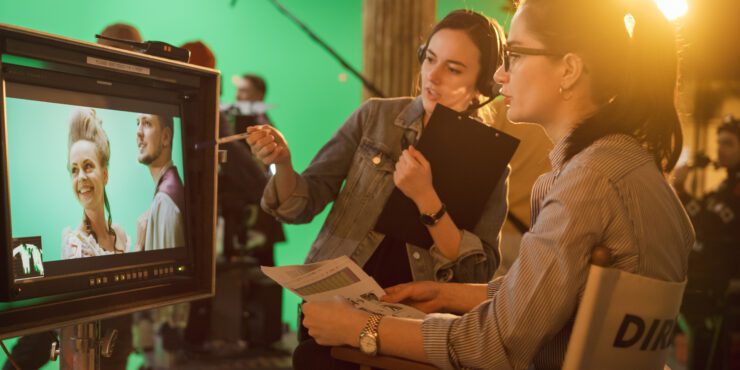 Female Director in Chair Looks at Display talks with Assistant, Shooting Blockbuster. Green Screen Scene