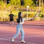 Student playing tennis on an outdoor court at Curtin Stadium.
