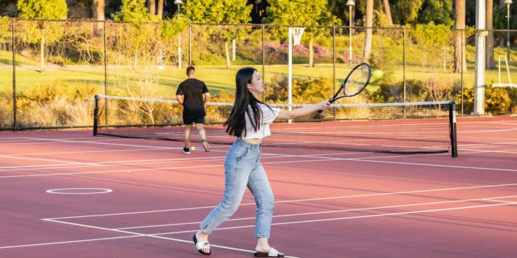 Student playing tennis on an outdoor court at Curtin Stadium.