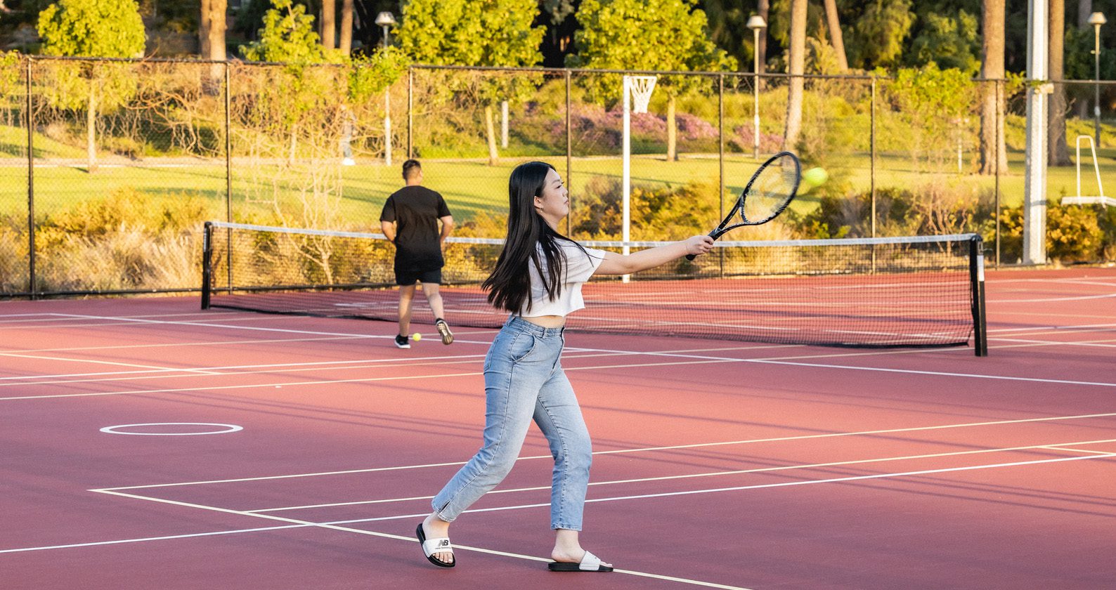 Student playing tennis on an outdoor court at Curtin Stadium.