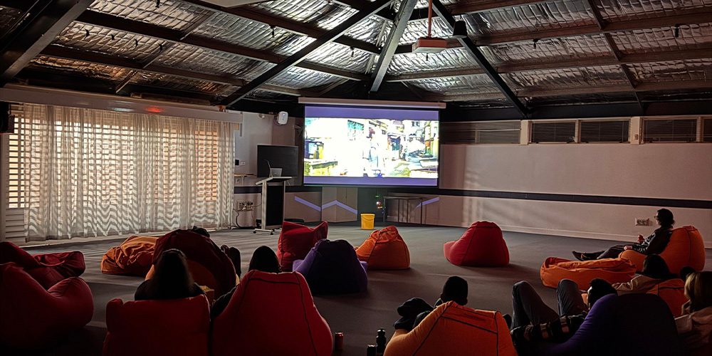 Students sit in beanbags watching a movie on a projector.