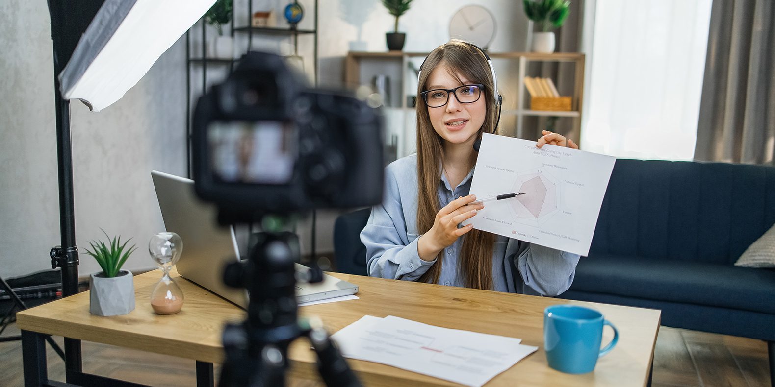 Business woman in glasses recording presentation on camera.