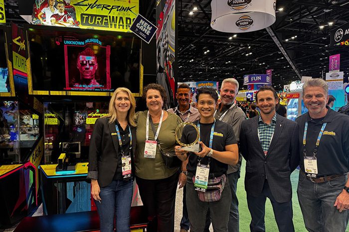 Creative team stand in front of an arcade game