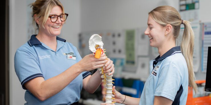 Physiotherapy students reviewing a spine model during clinic training.
