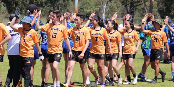 Curtin students in team uniforms walking together on a grass field during a university sports competition.