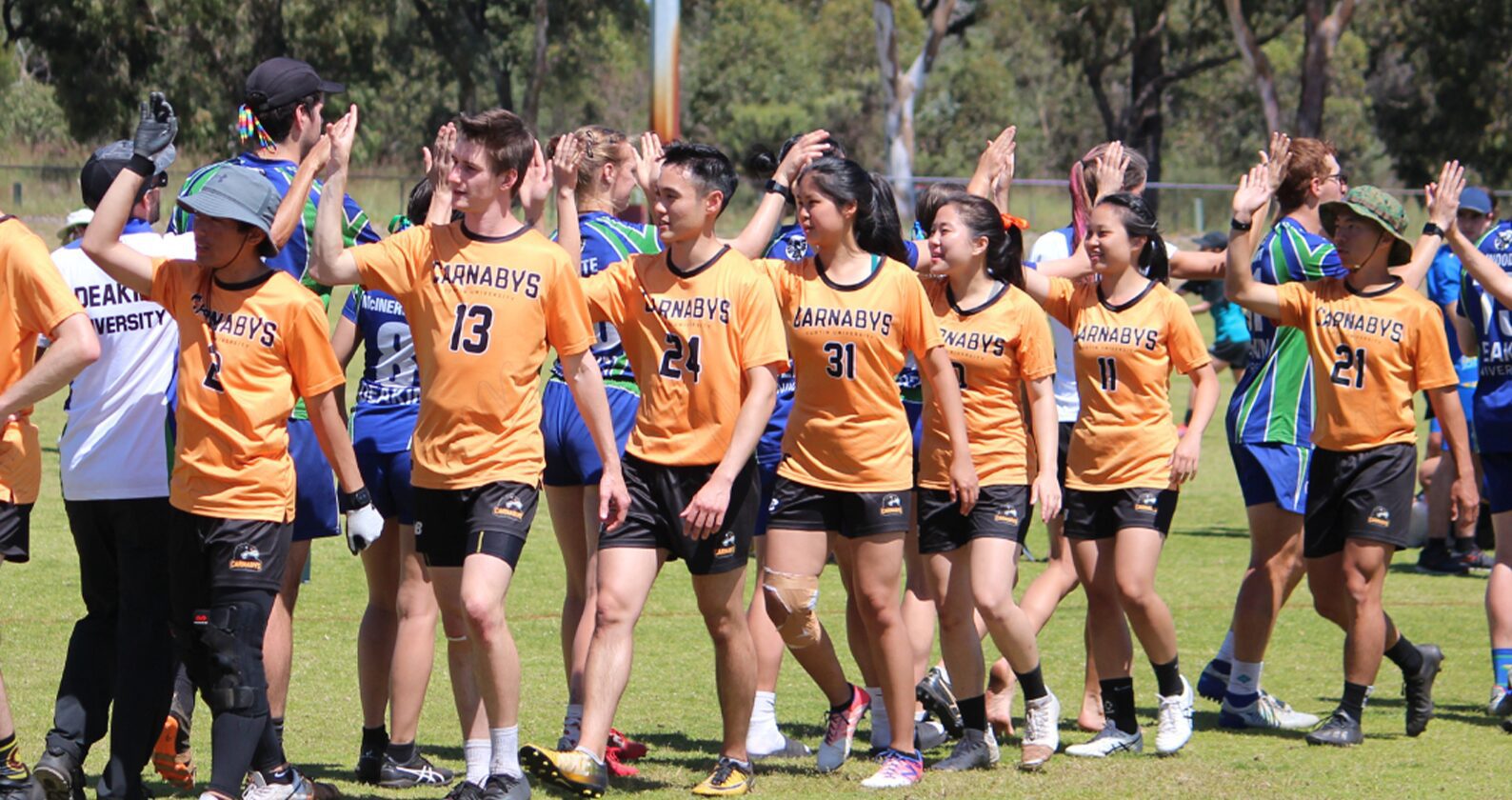 Curtin students in team uniforms walking together on a grass field during a university sports competition.