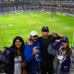 Four people standing in a stadium holding Dockers scarves with a football field and crowd in the background. Provide your feedback on BizChat