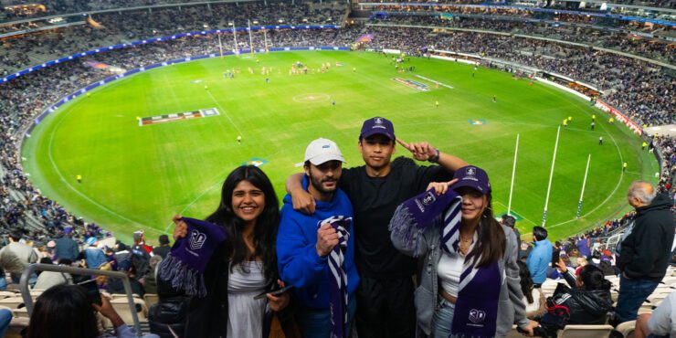 Four people standing in a stadium holding Dockers scarves with a football field and crowd in the background. Provide your feedback on BizChat