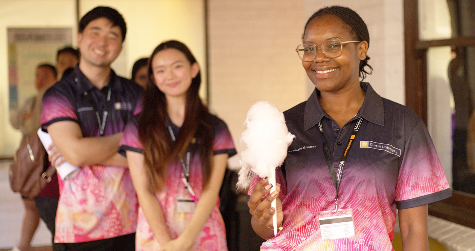 Student holding fairy floss in front of two other students on campus.