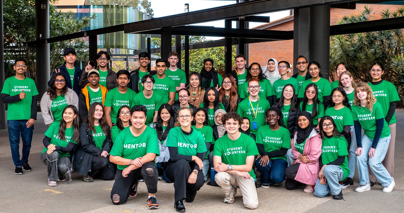 Group of Curtin student volunteers wearing green “Student Volunteer” shirts, posing together on campus.