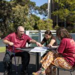 Three students talking outdoors on campus.