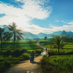 Breathtaking landscape of lush green rice fields and mountains under a vibrant blue sky in Jawa Barat, Indonesia.