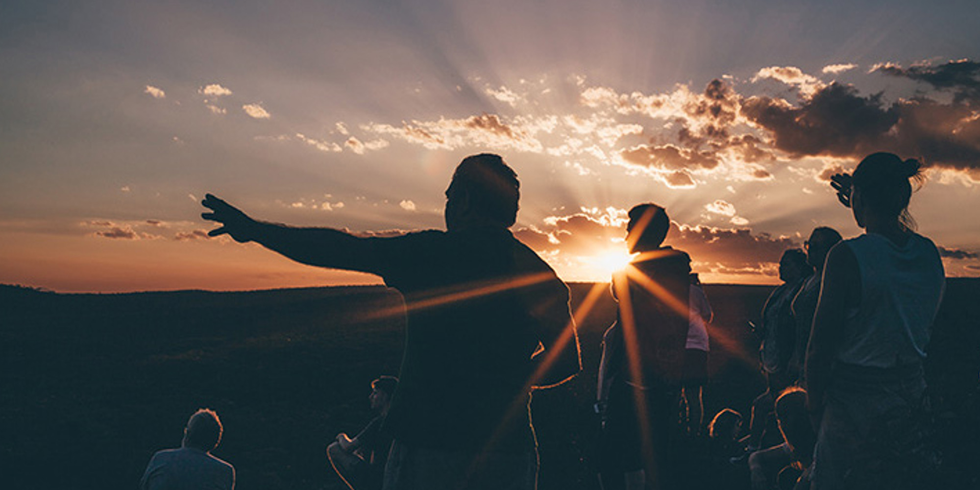 Group of people admiring the land at sunset