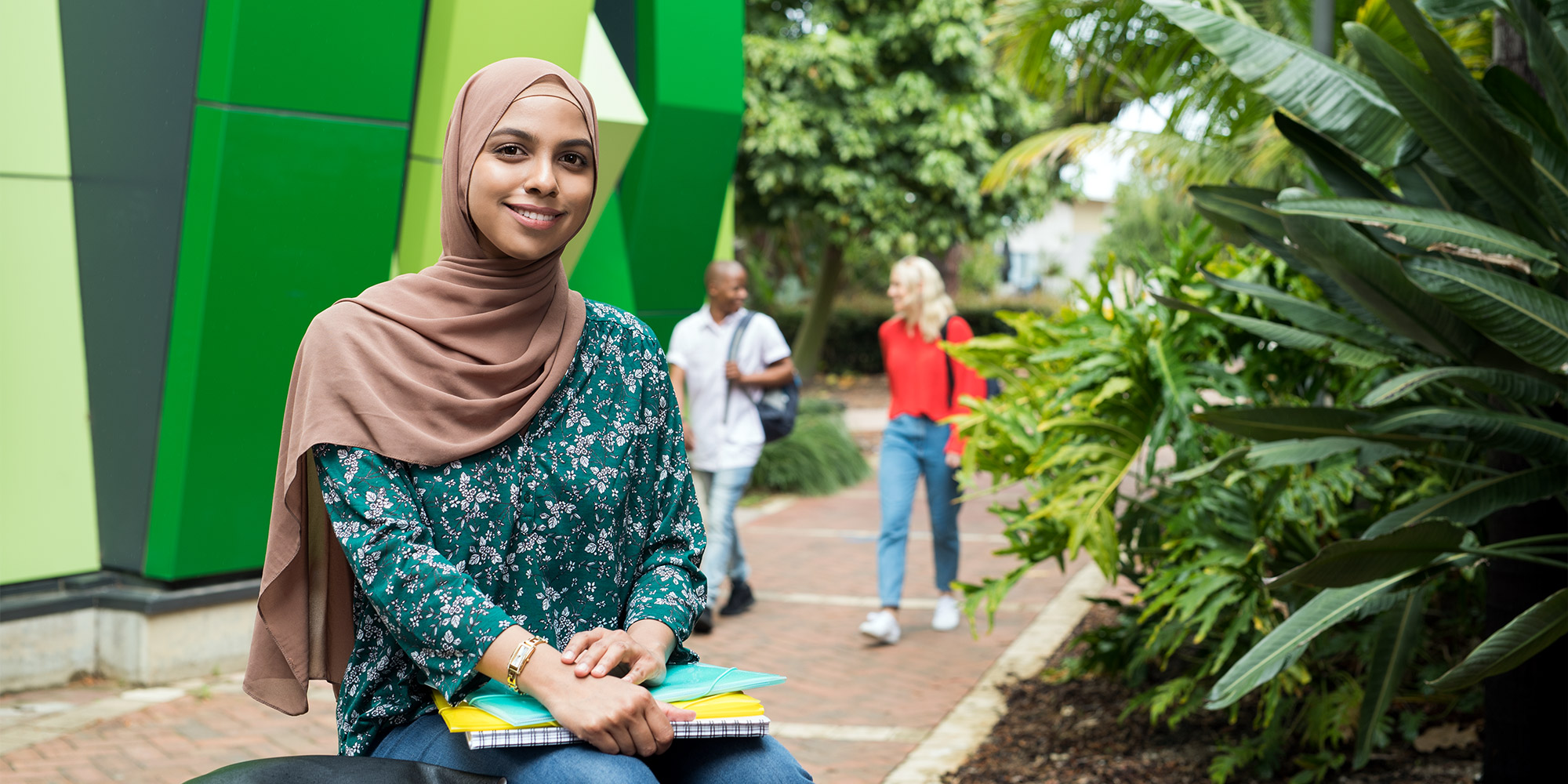 Female researcher holding some notebooks and sitting outside