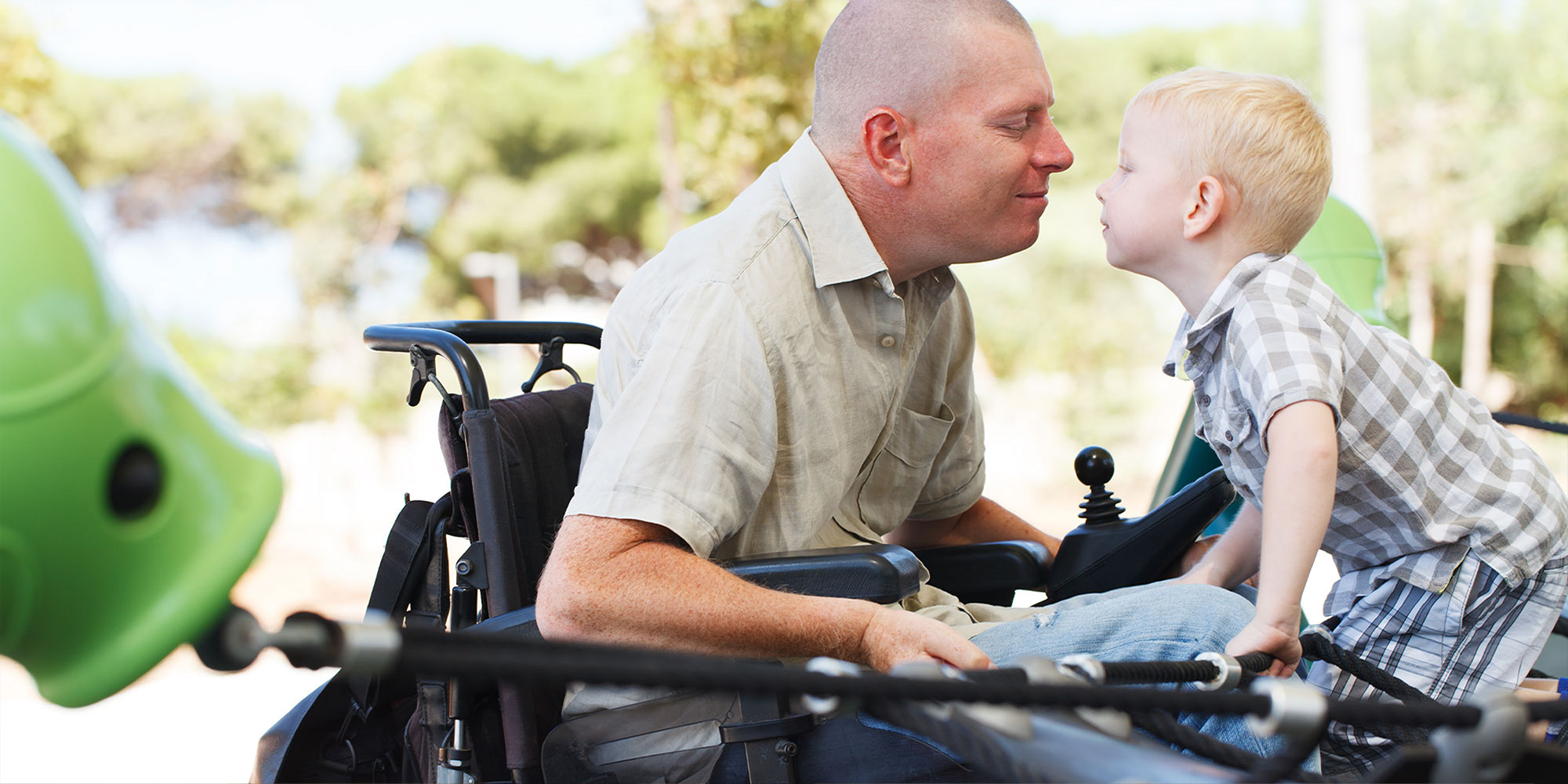 A man in a wheelchair and a young boy enjoying a community park together