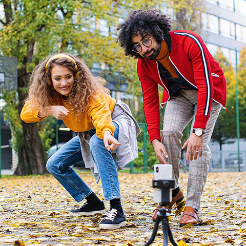 Malen and female students filming outside using a cell phone