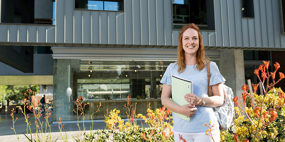 female student standing in front of university building