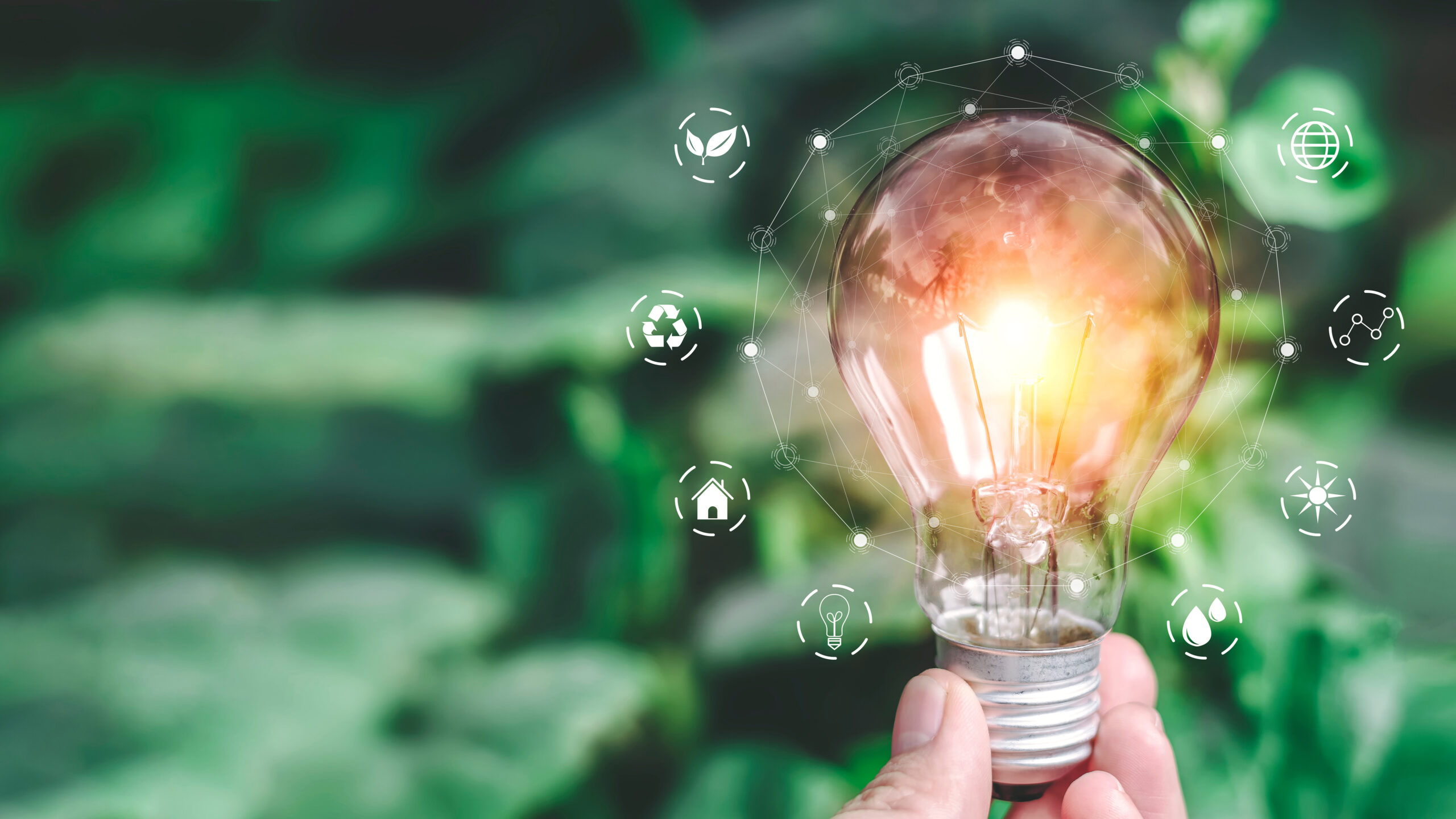 A lightbulb held by a hand, with small icons orbiting the bulb, which is on.