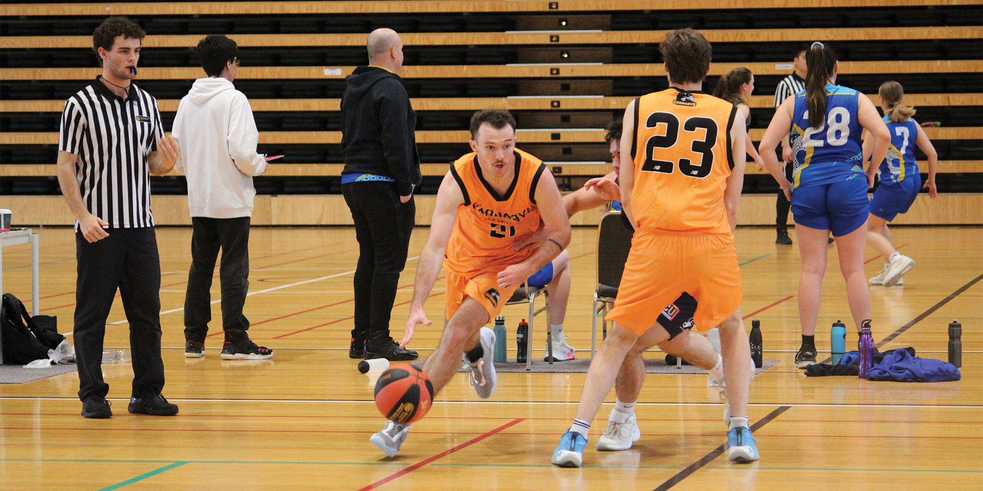 Student wearing orange shirt bounces a basketball in a stadium