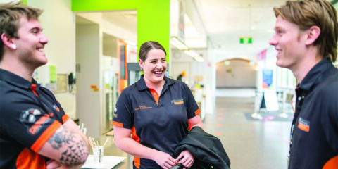 Three Curtin Stadium staff members laugh while talking to each other