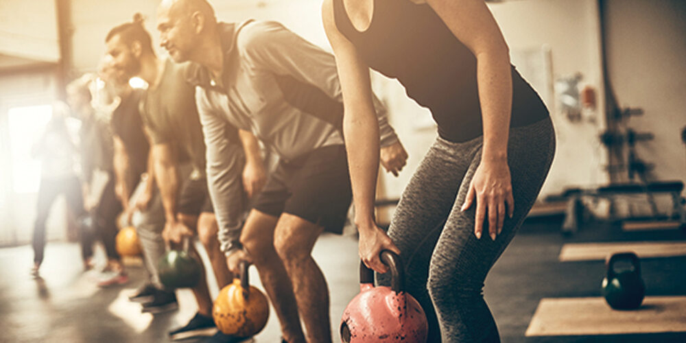 Gym members standing in a row holding kettle bells