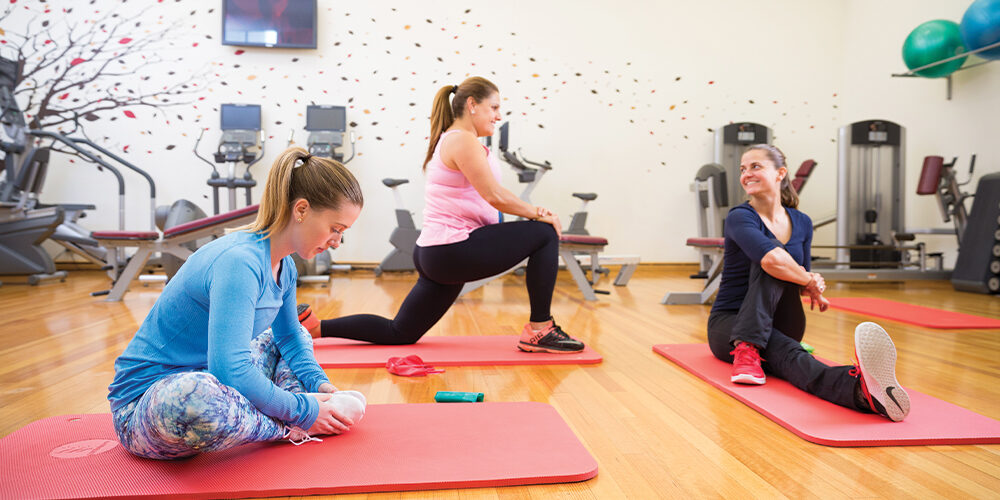 Three women sitting on yoga mats indoors