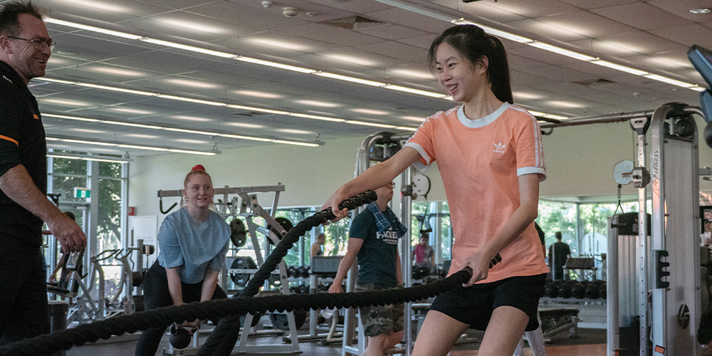 Student using battle ropes in the gym