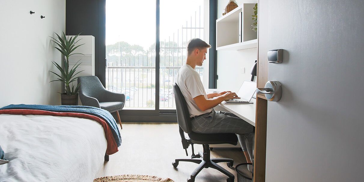 A man sitting at his desk and typing on his computer.