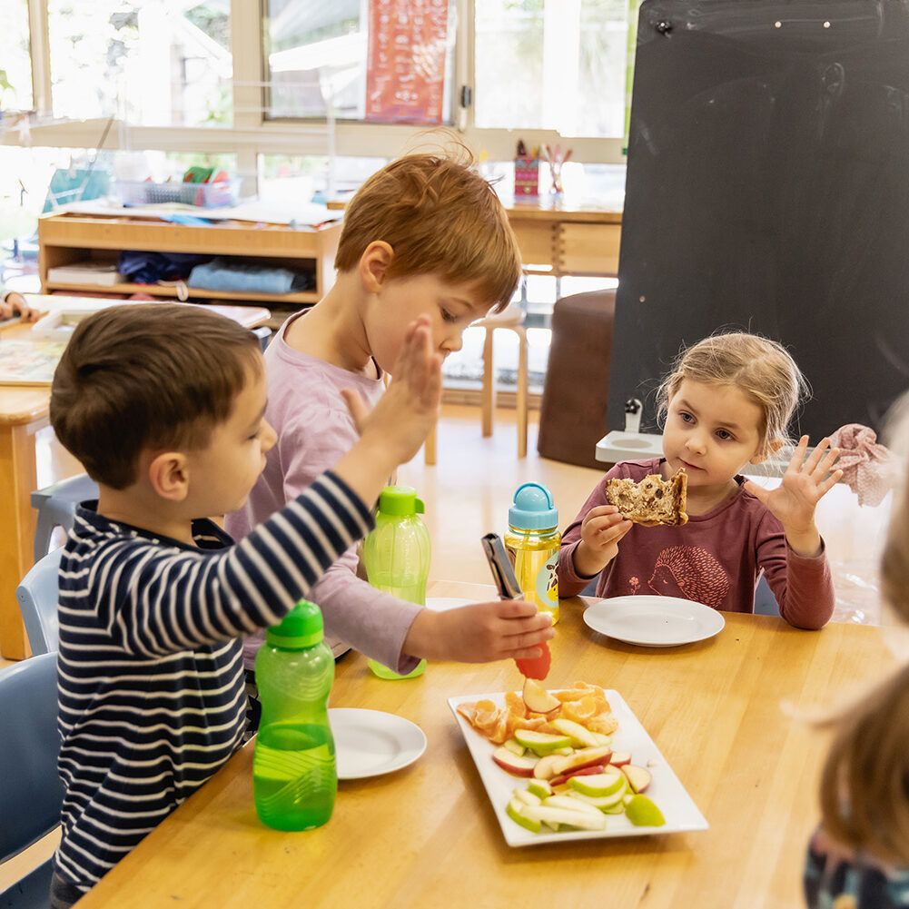 Three young children at table eating