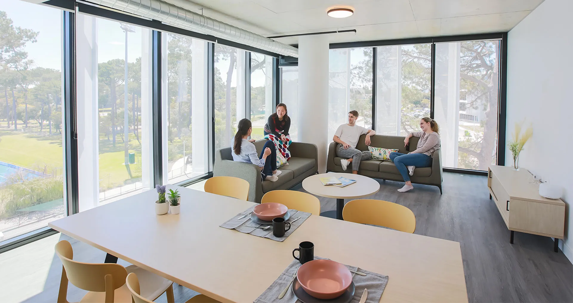 Students sit on couches in a living room chatting.