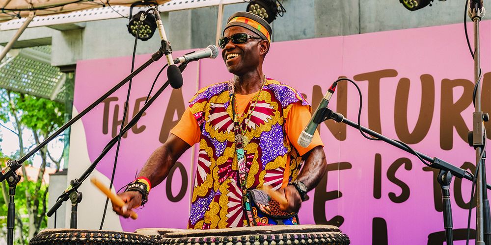 A drummer on stage wearing colourful attire - play video