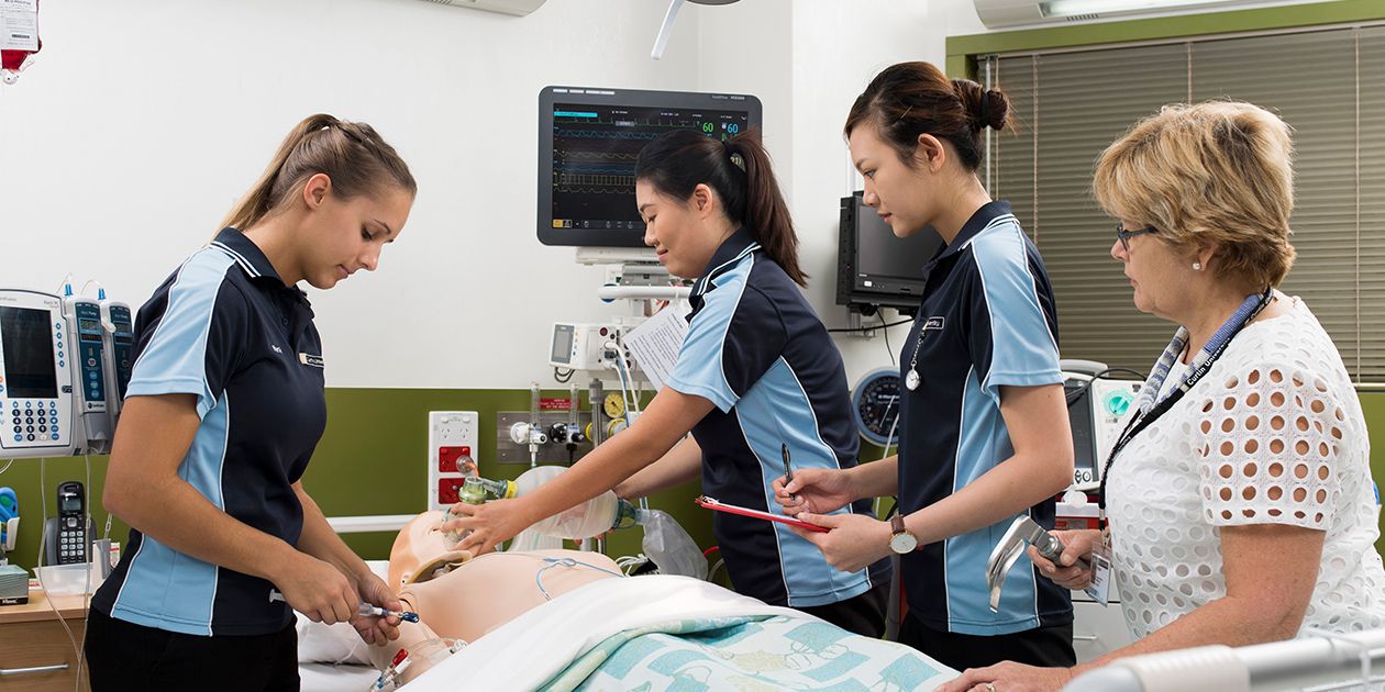 Three students and one supervisor practicing nursing on dummy