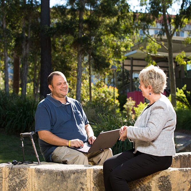 Man in wheelchair talking to a woman, outdoors