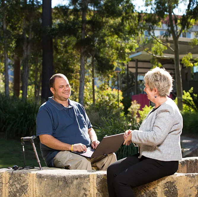 Man in wheelchair talking to a woman, outdoors