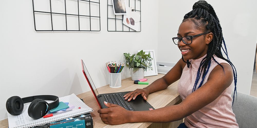 Student sitting at a desk working on a red laptop