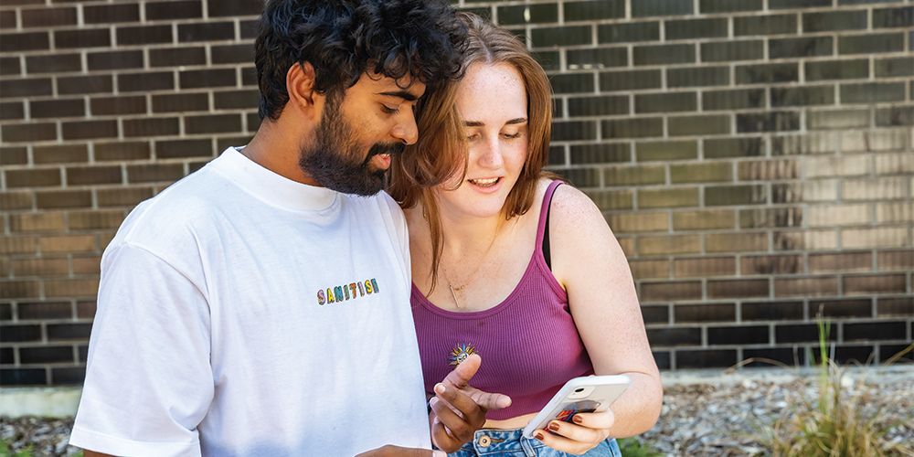 Two students looking at a mobile phone