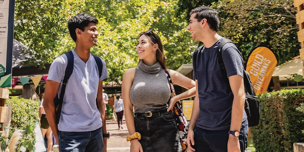 Three students talking outside on campus