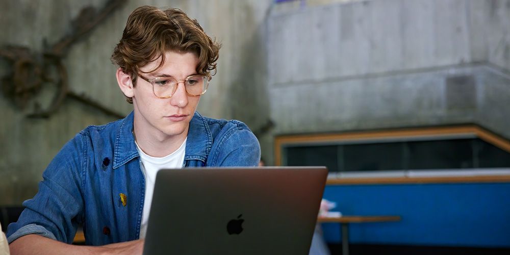 Student looking at a grey laptop.