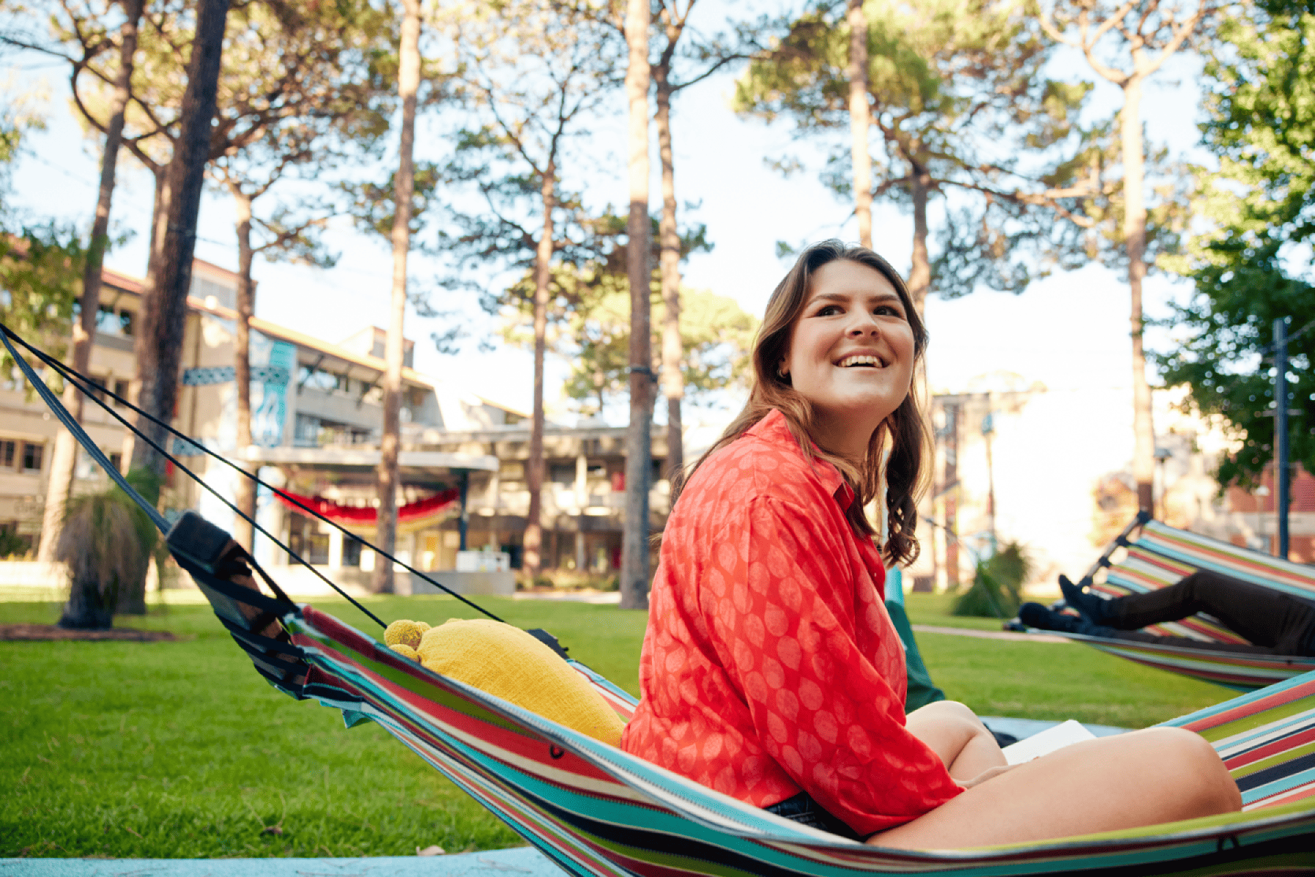 Student smiles whilst sitting on a hammock