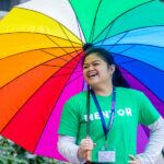 A smiling female student wearing a green t-shirt that says 