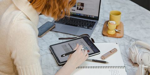 A female student studying using a laptop and an iPad