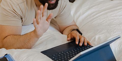 A male student on a video call using his iPad and waving at the camera